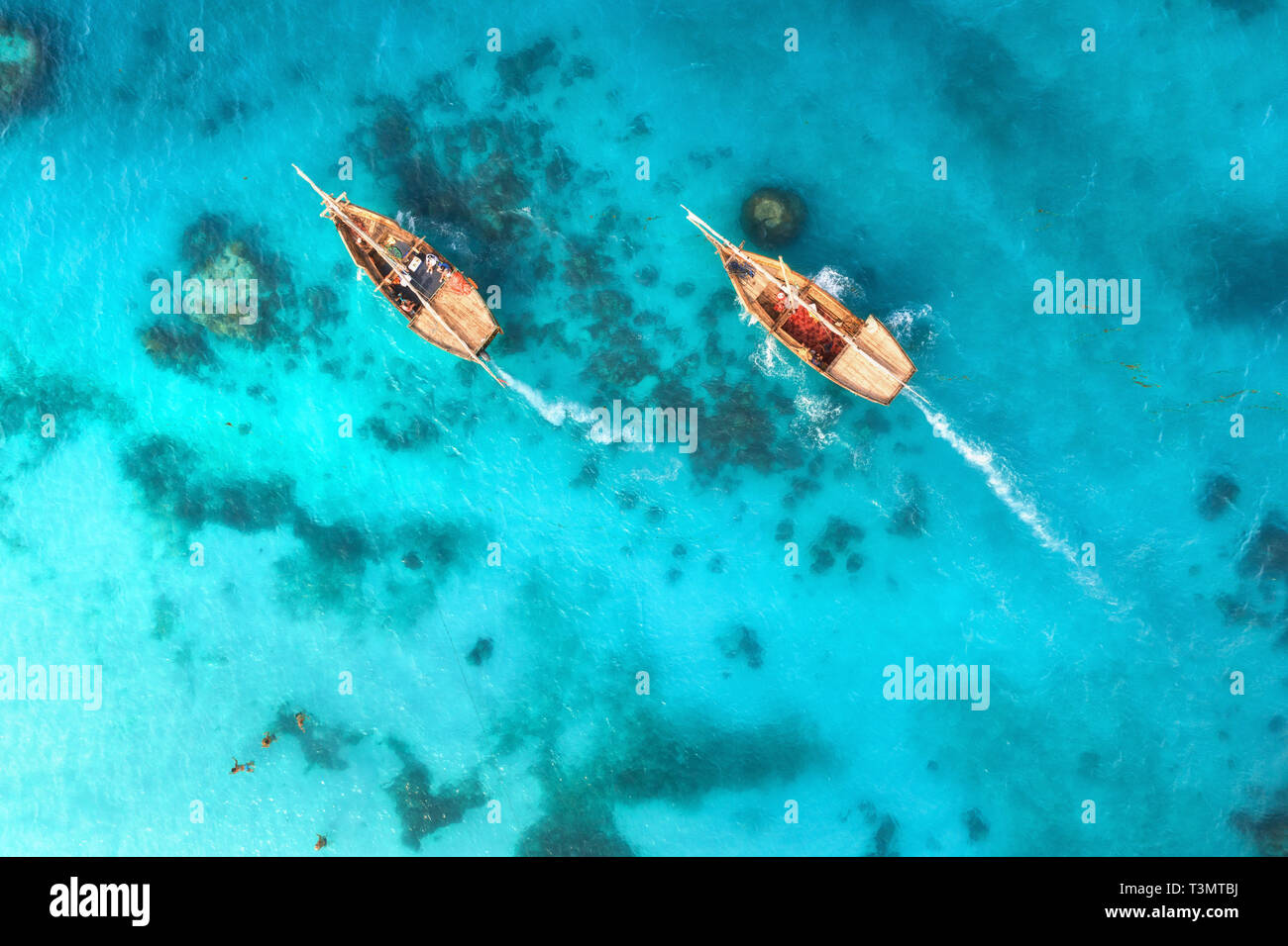 Aerial view of the fishing boats in clear blue water at sunset in ...