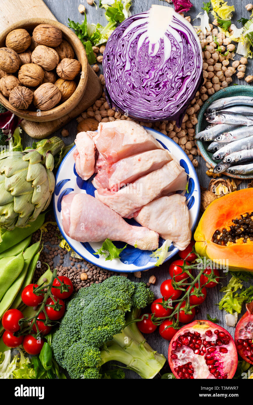 high angle view of a pile of unprocessed food, such as different raw fruits and vegetables, some legumes and nuts, some pieces of chicken and some raw Stock Photo