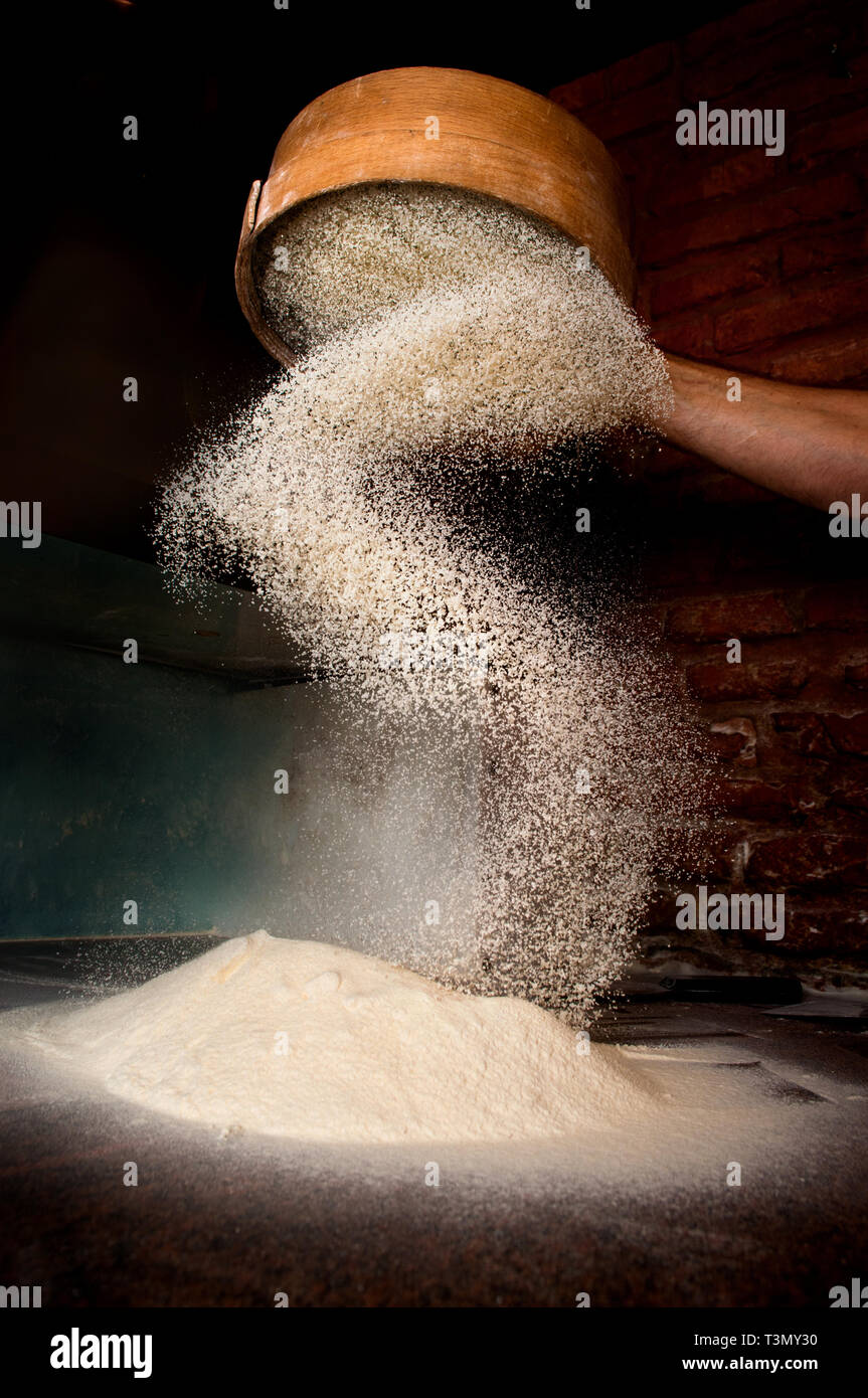 Sifting flour from old sieve. Stock Photo