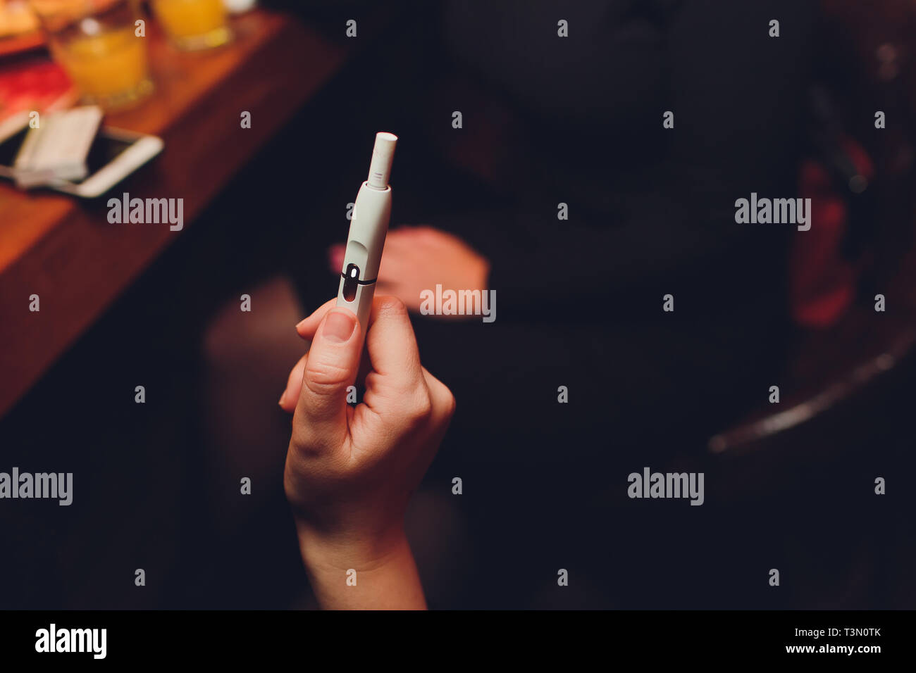 IQOS heat-not-burn tobacco product technology. Woman holding e-cigarette in  his hand before smoking Stock Photo