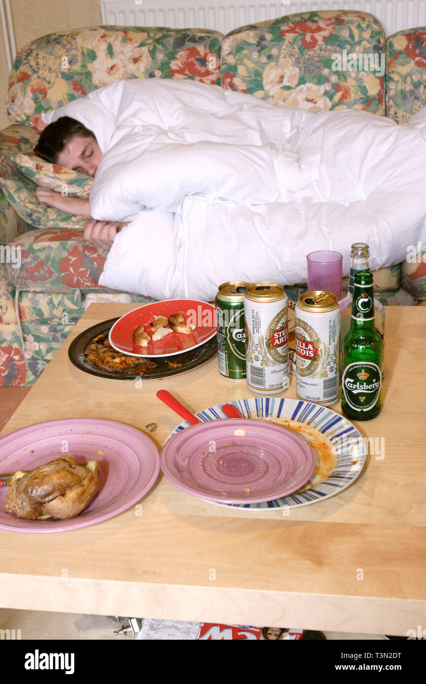 Teenage man asleep on the living room sofa after a night of binge drinking in town. Newport, South Wales 03/11/2005 Stock Photo