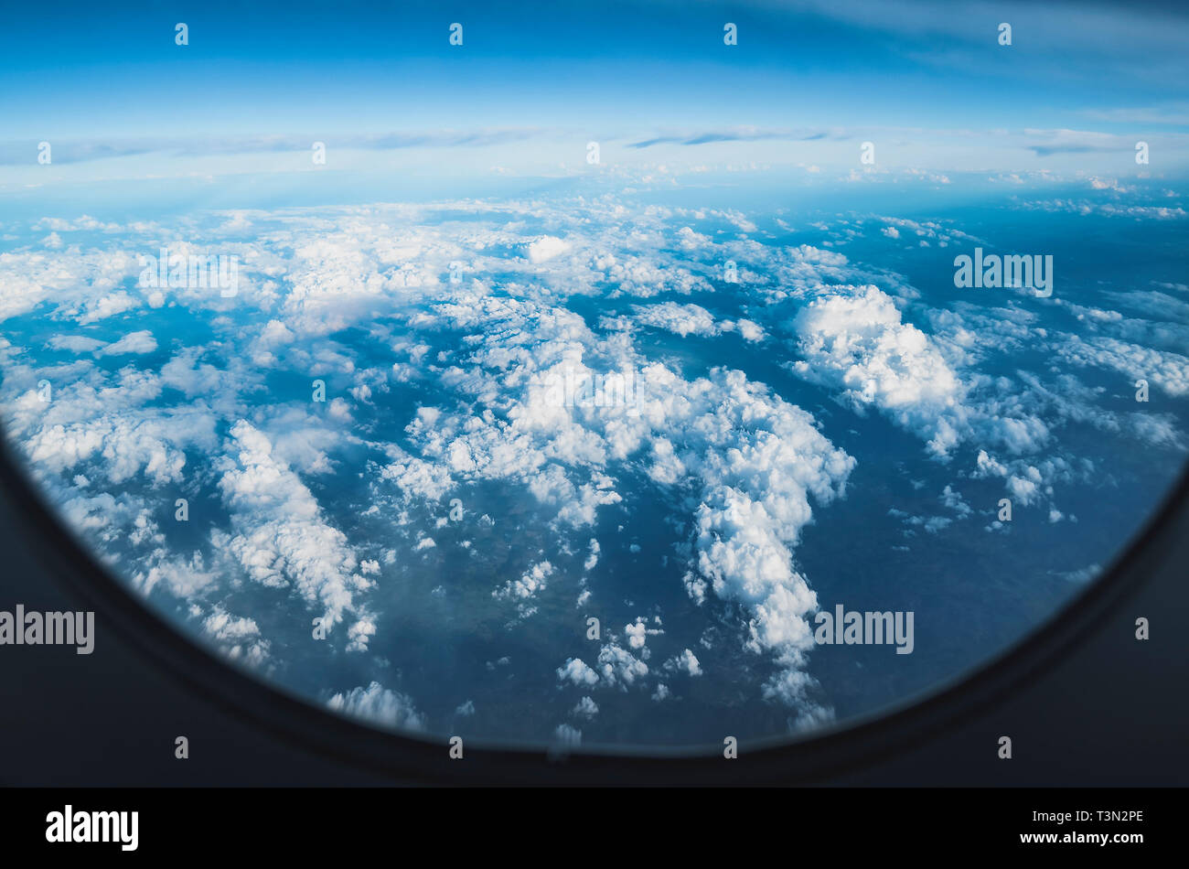 View of the sky above clouds over the earth through the airplane window ...