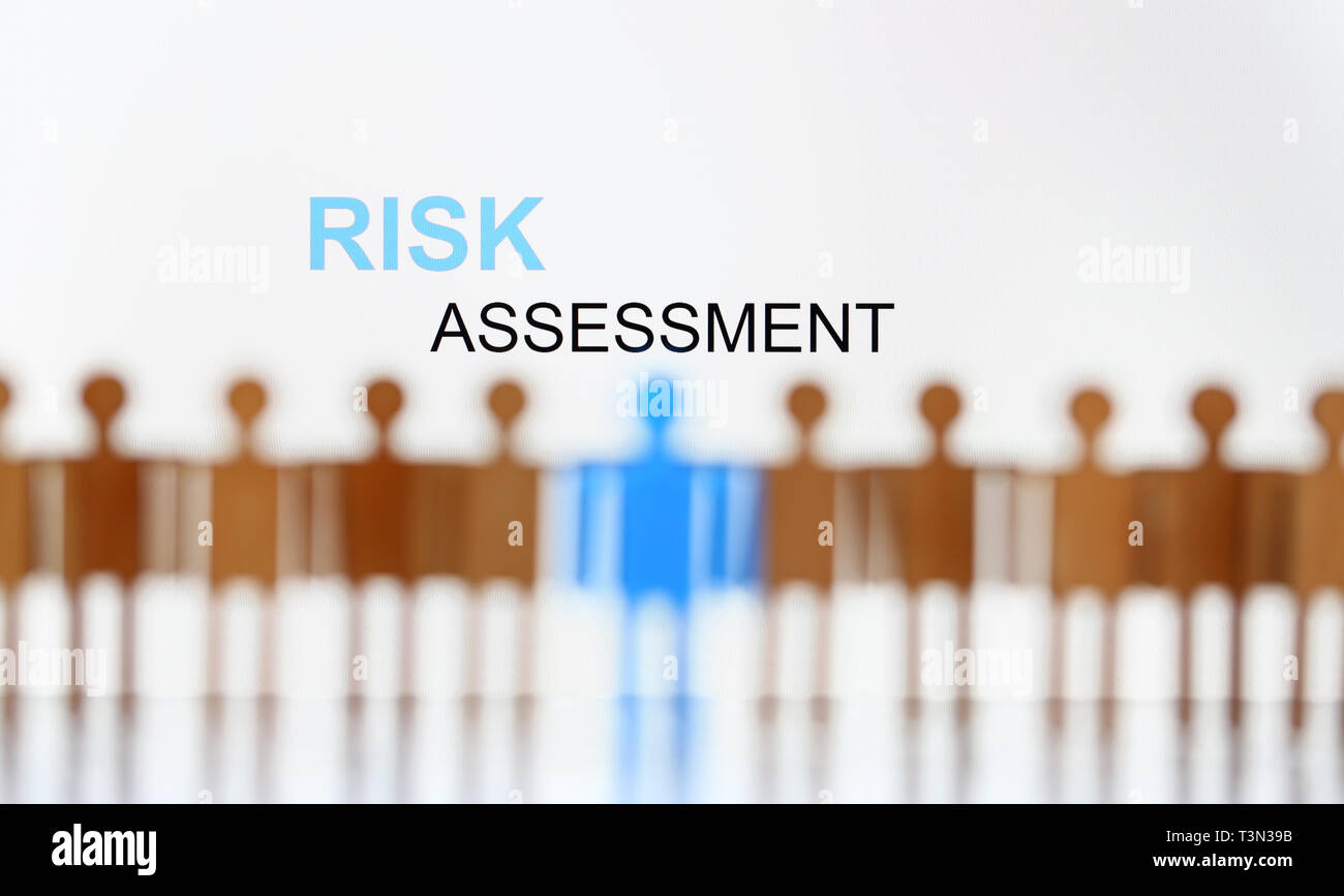 Risk assessment sign above line of toy human figures Stock Photo Alamy