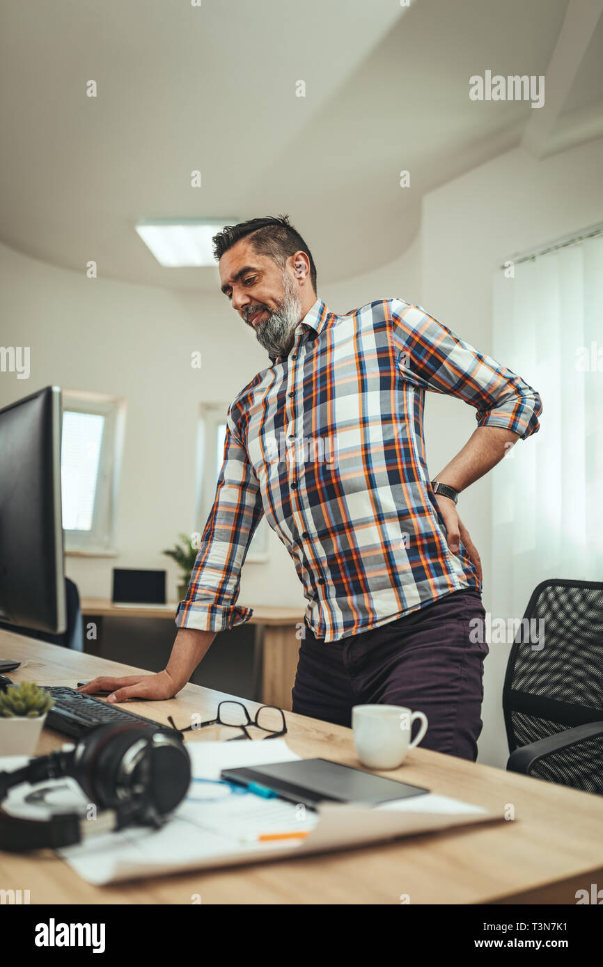 Young handsome overworked businessman standing in the office having
