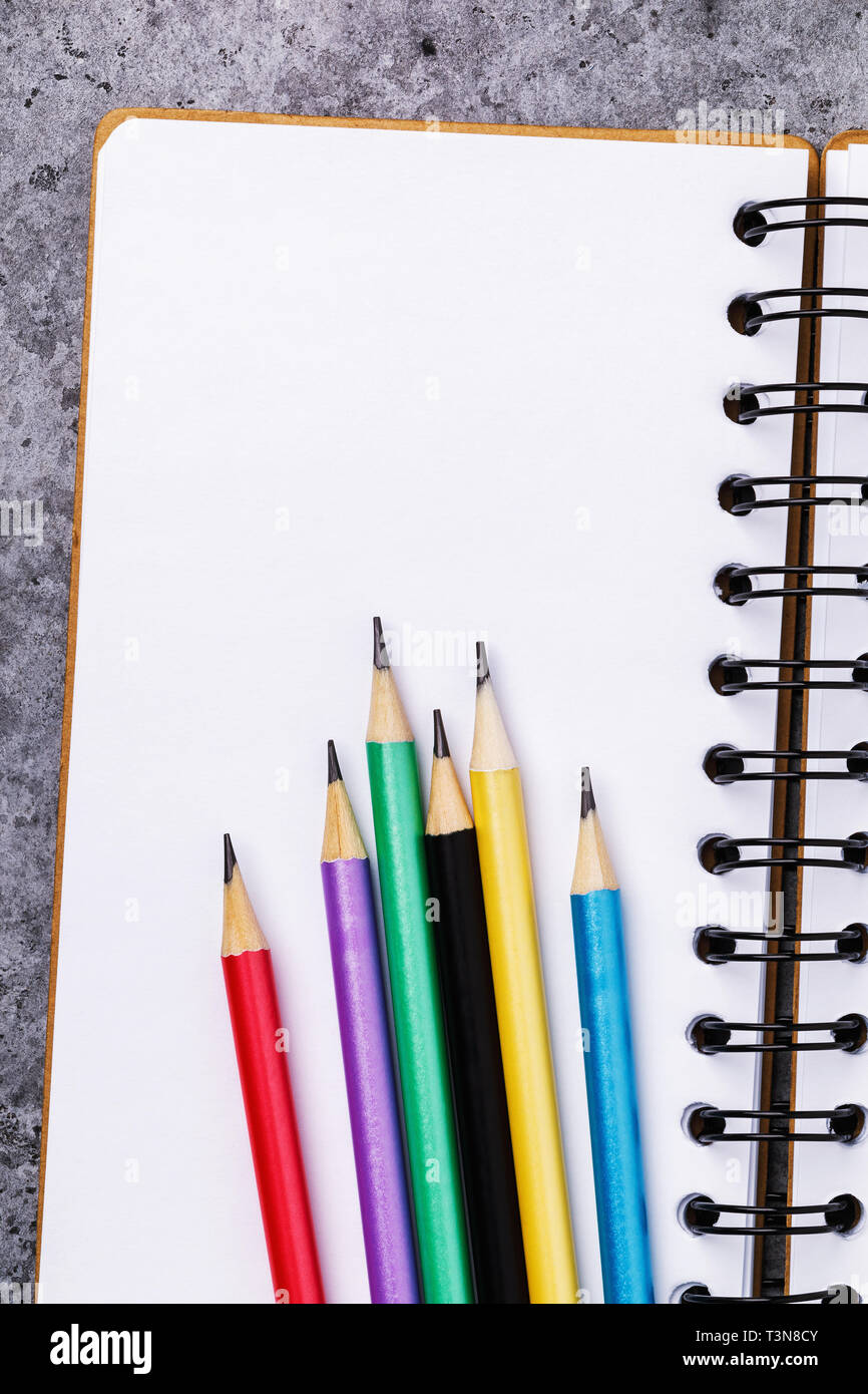 Pencils on a notebook with copy space, top view Stock Photo