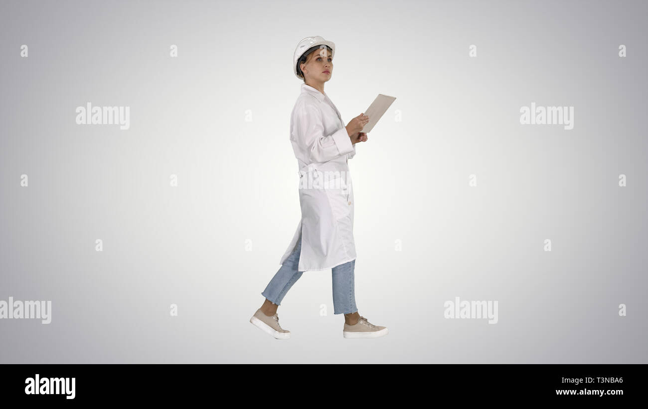 Young technician inspecting and taking necessary notes on digital tablet on gradient background. Stock Photo