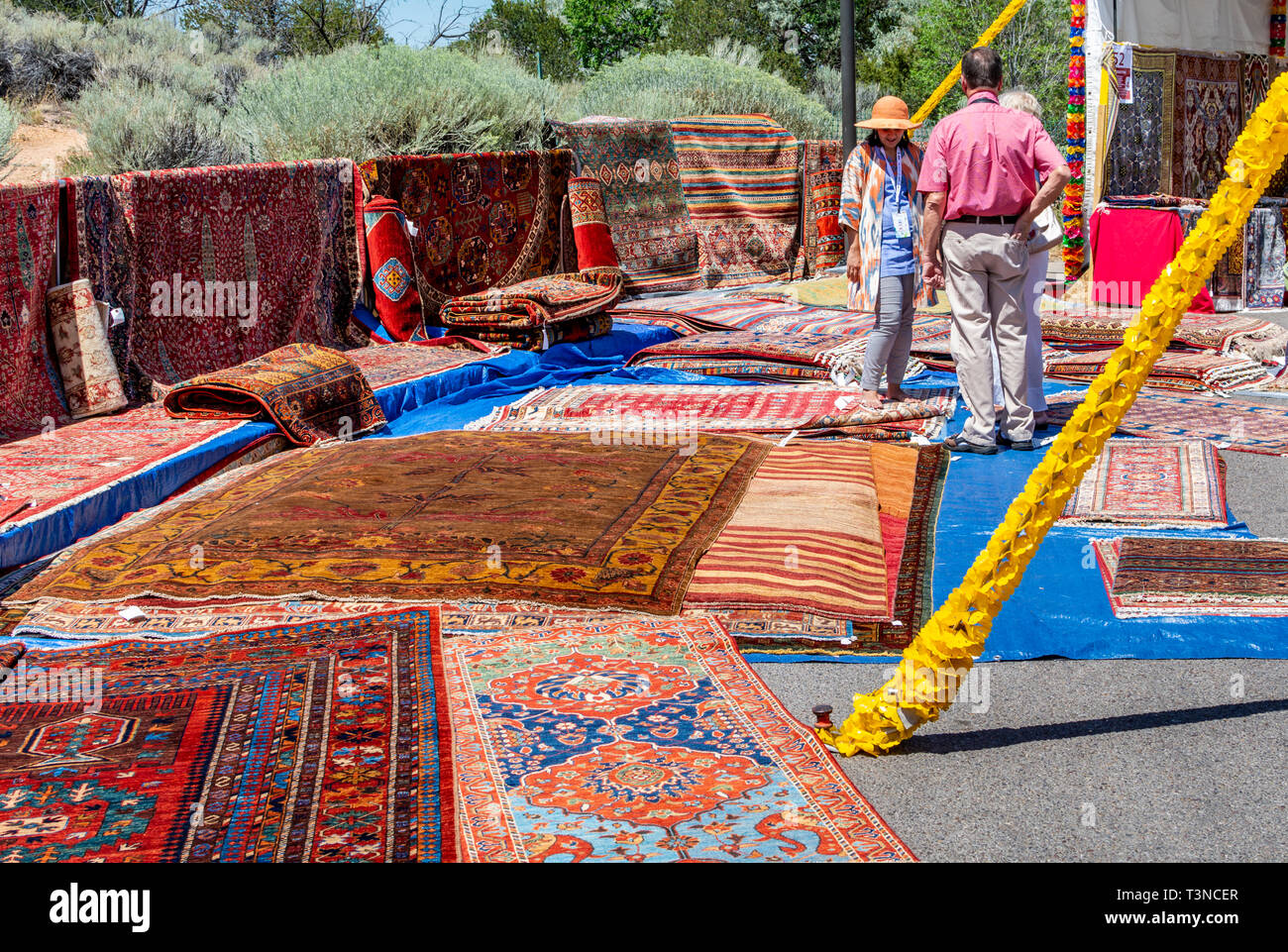 Barefoot woman shops for rugs from Uzbekistan at the 2019 International Folk Art Market, Santa Fe, New Mexico, USA. Stock Photo