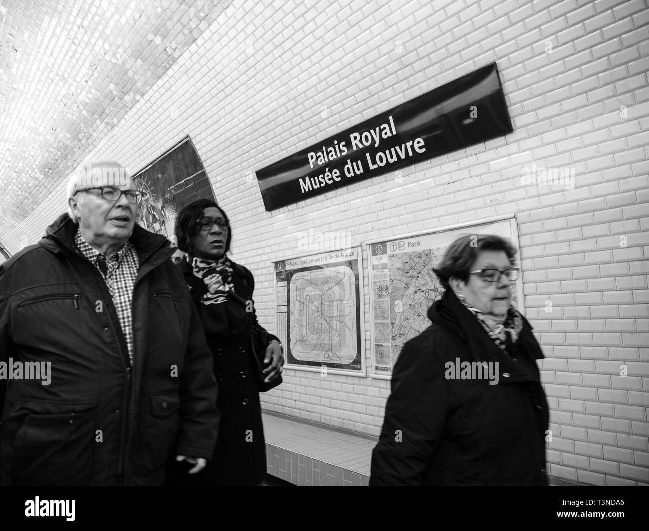 Paris, France - Mar 19, 2019: Group of commuters people walking inside Paris Metro at the Palais Royal Musee du Louvre museum with map of Paris on the tiles white wall Stock Photo