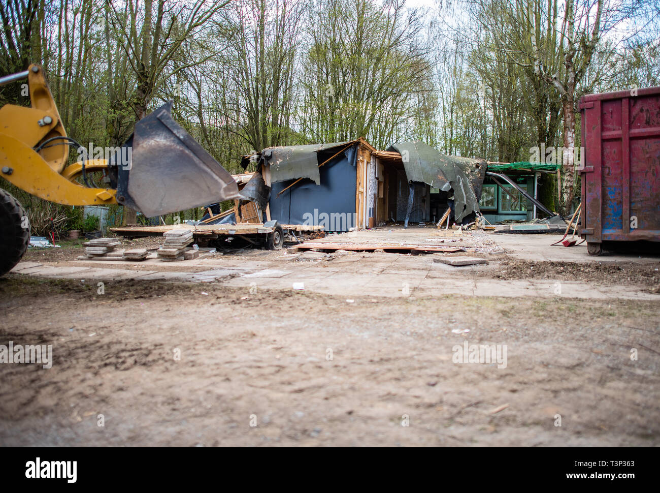 11 April 2019, North Rhine-Westphalia, Lügde: An excavator stands in front of the plot of the alleged perpetrator at the camping site Eichwald in the district Elbrinxen and demolishes the complete complex. The campsite operator has the crime scene demolished, where several children were abused and filmed. The demolition work will continue until the weekend due to the large quantity. Photo: Guido Kirchner/dpa Stock Photo