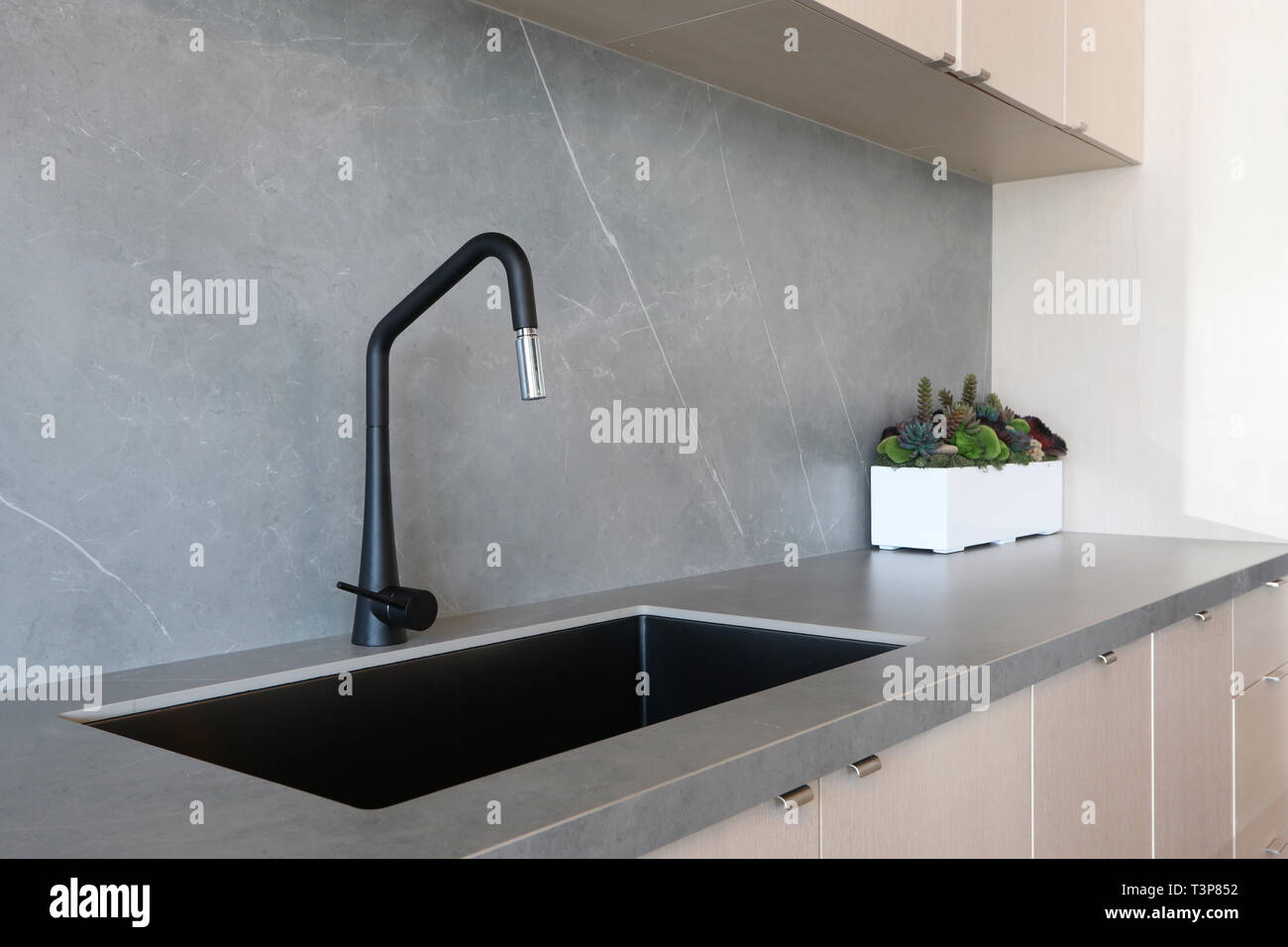 A Black Sink And Matt Finish Black Faucet Set Against A Grey