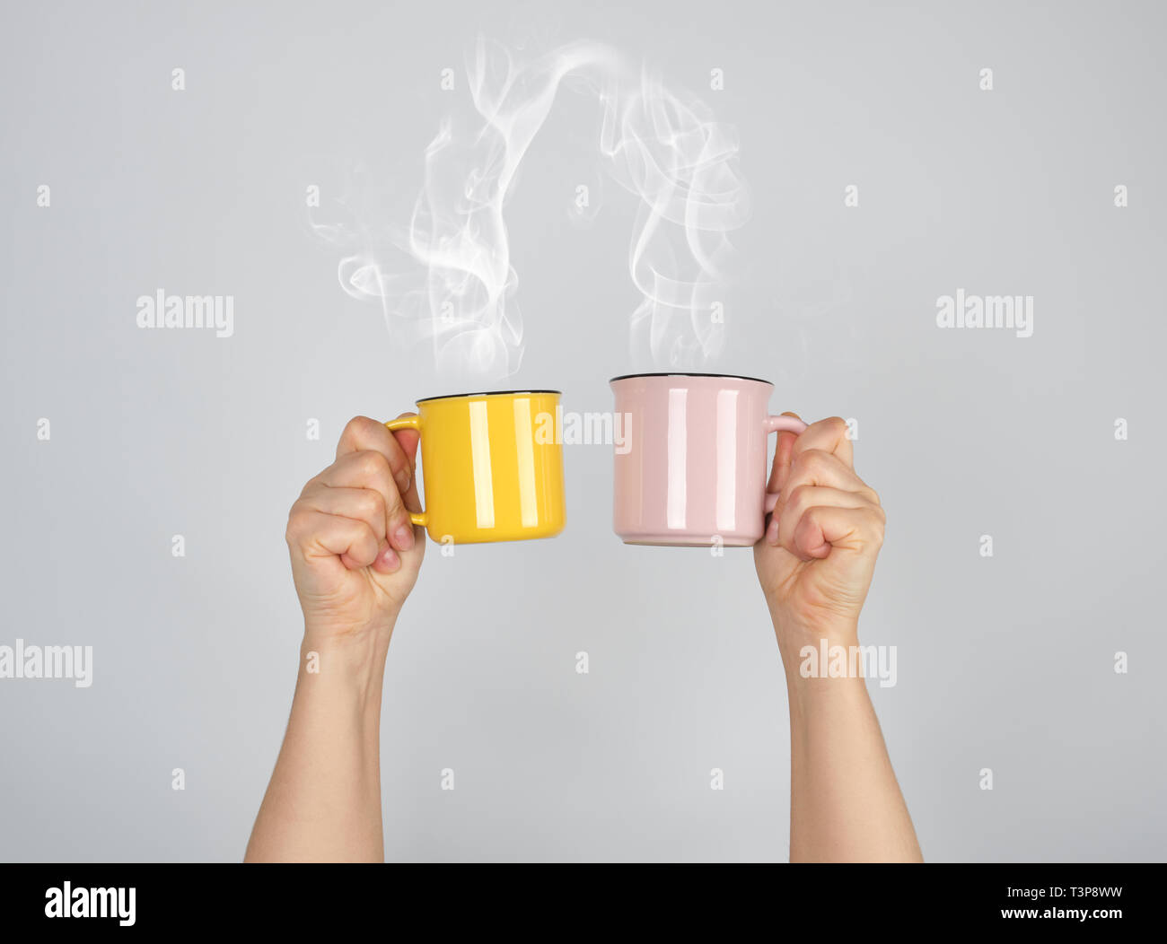 two raised hands up with ceramic cups, thick steam comes out of the mug