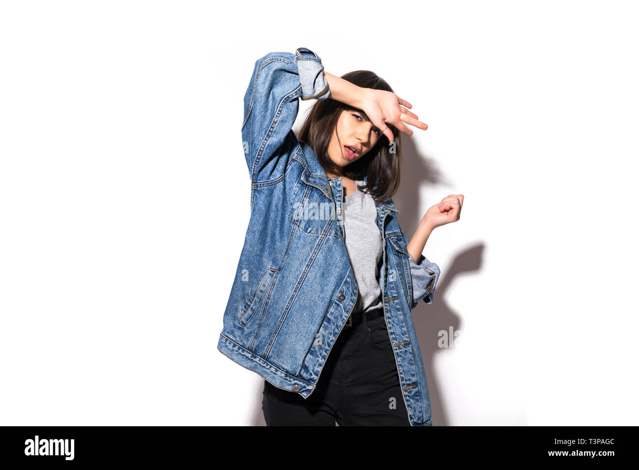 Portrait of a young woman dressed in jeans jacket standing isolated on a white background. Look at camera. Stock Photo