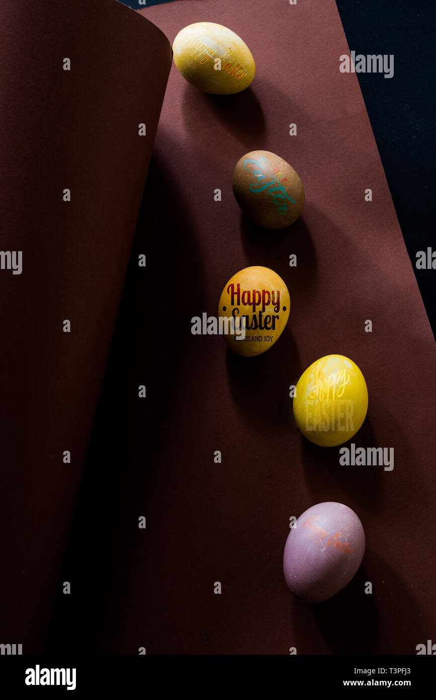 Colored eggs on a brown background , brown and black background, text " happy easter" Stock Photo