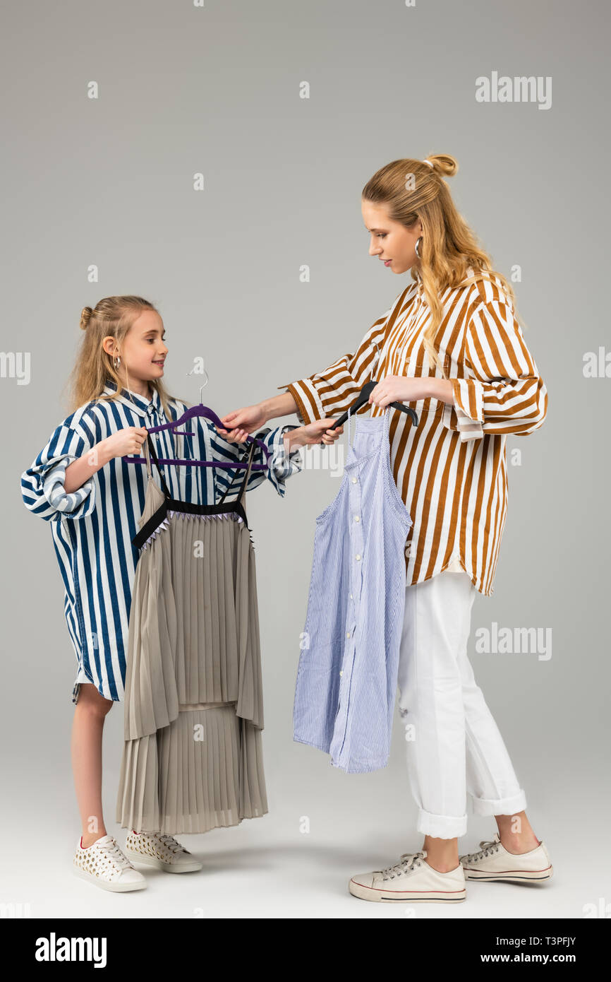 Attentive experienced adult lady proposing her young sister another dress Stock Photo