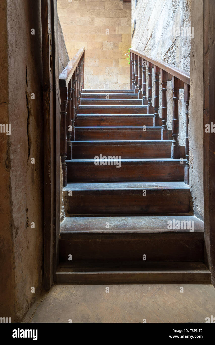 Open wooden door revealing wooden old staircase going up located at the