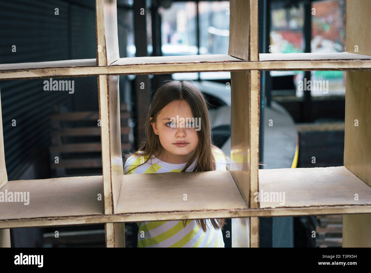 A pretty girl looking out from behind a cage-shaped structure. Play concept Stock Photo