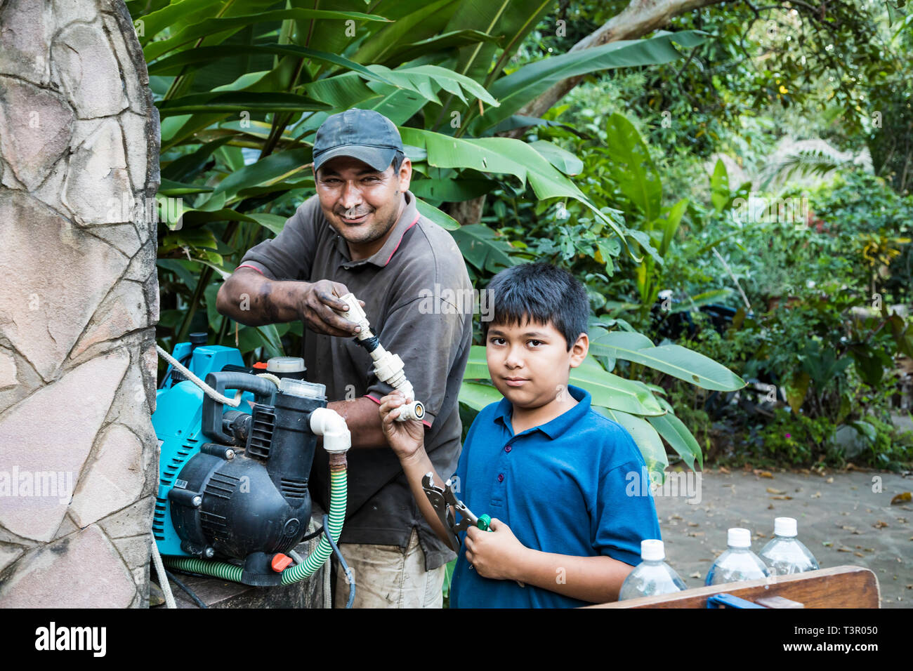 Colonia Independencia, Paraguay - April 17, 2018: A Paraguayan boy helps his father repair a pump. Stock Photo