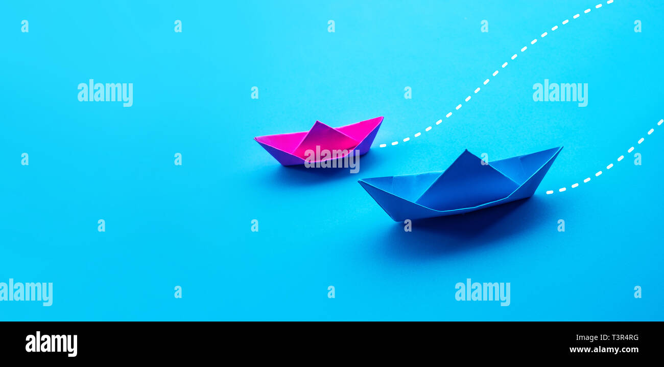 Business competition or partner concepts with two boat paper on blue worktable background.situation challenge Stock Photo