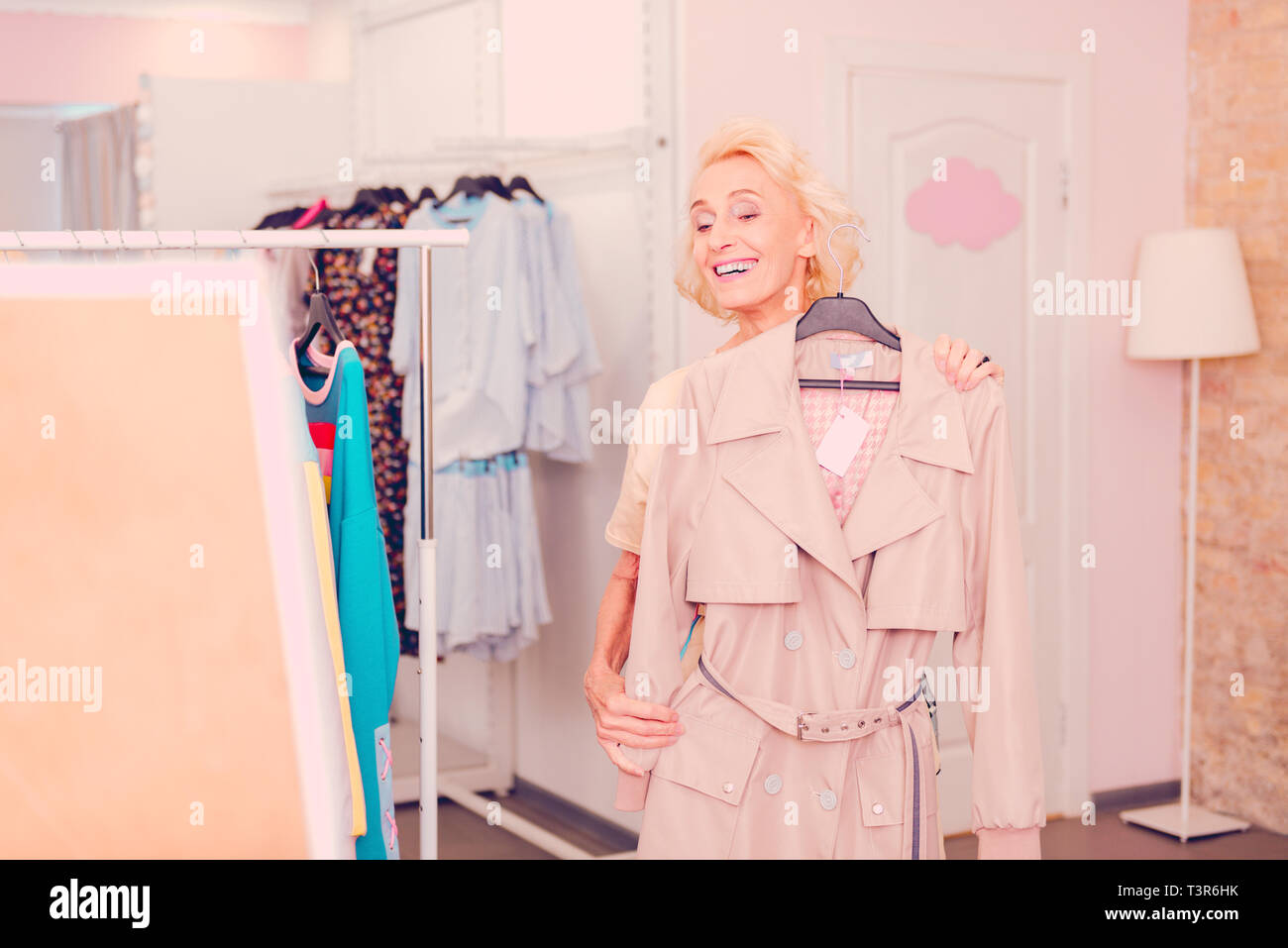 Smiling senior woman fitting a new trench Stock Photo Alamy