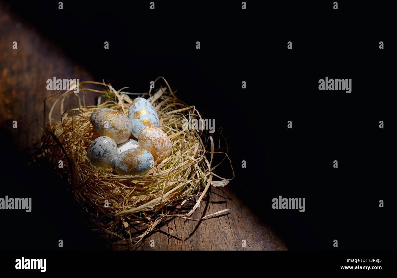 Decorative easter eggs in nest on wooden table Stock Photo