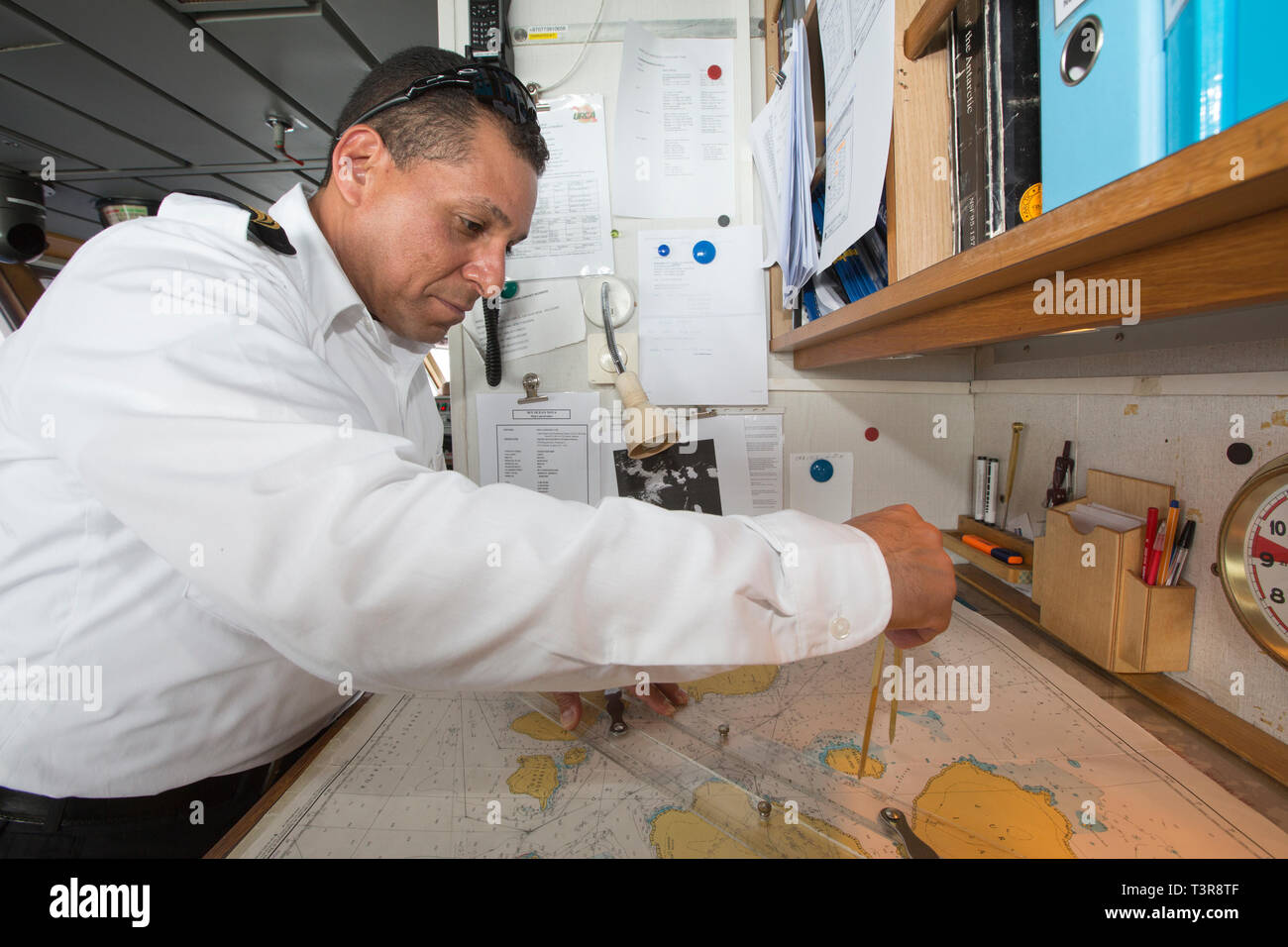 The ships navigator using navigation equipment and a sea chart of the