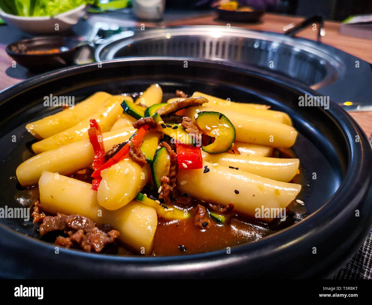a close up of a Korean Tteokbokki rice dumplings black dish in an korean ethnic restaurant with