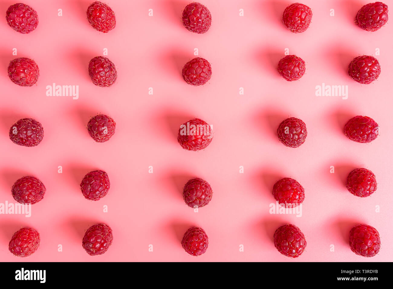 Pattern made from fresh raspberries, top view, flat lay pattern, isolated on a light pink background. Stock Photo
