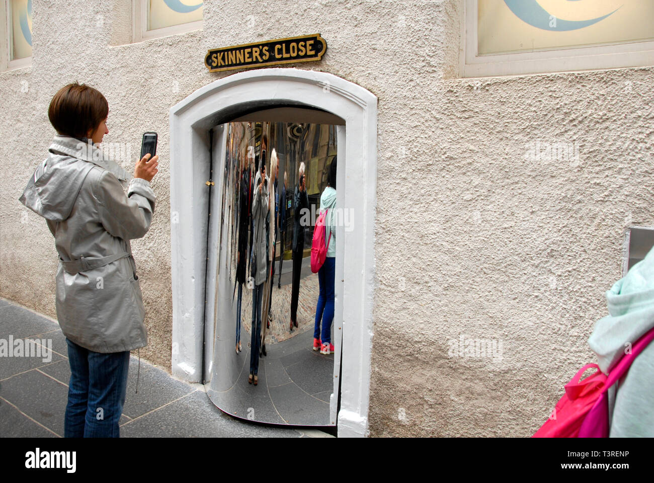 Young lady taking photograph of herself in distorting mirror, Edinburgh, Scotland Stock Photo