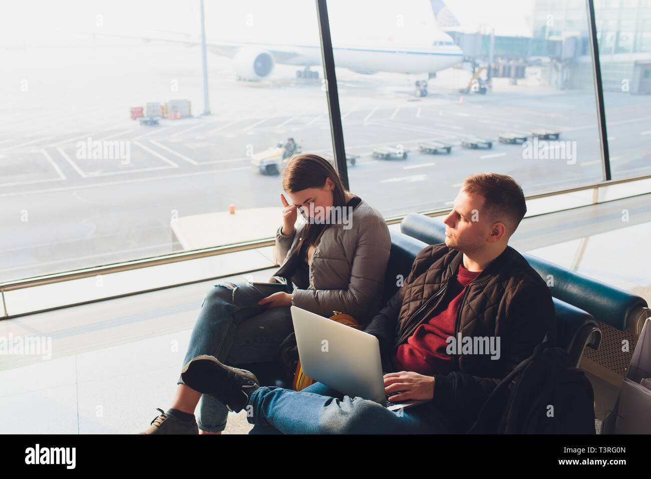 Elegant business couple working with laptop and phone sitting at the waiting hall in the airport