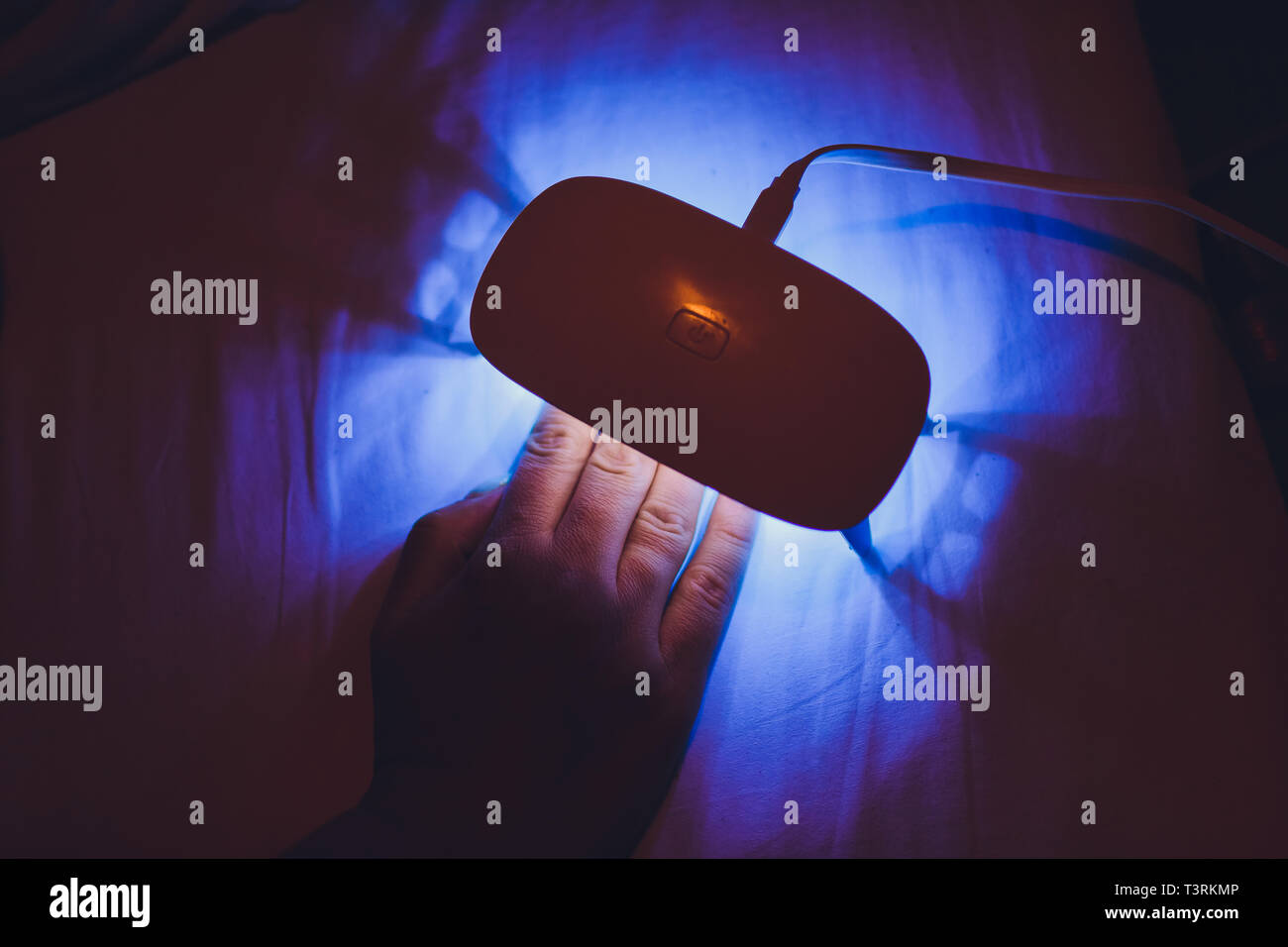 Woman includes lamp and dries her nails with shellac in UV lamp. Close