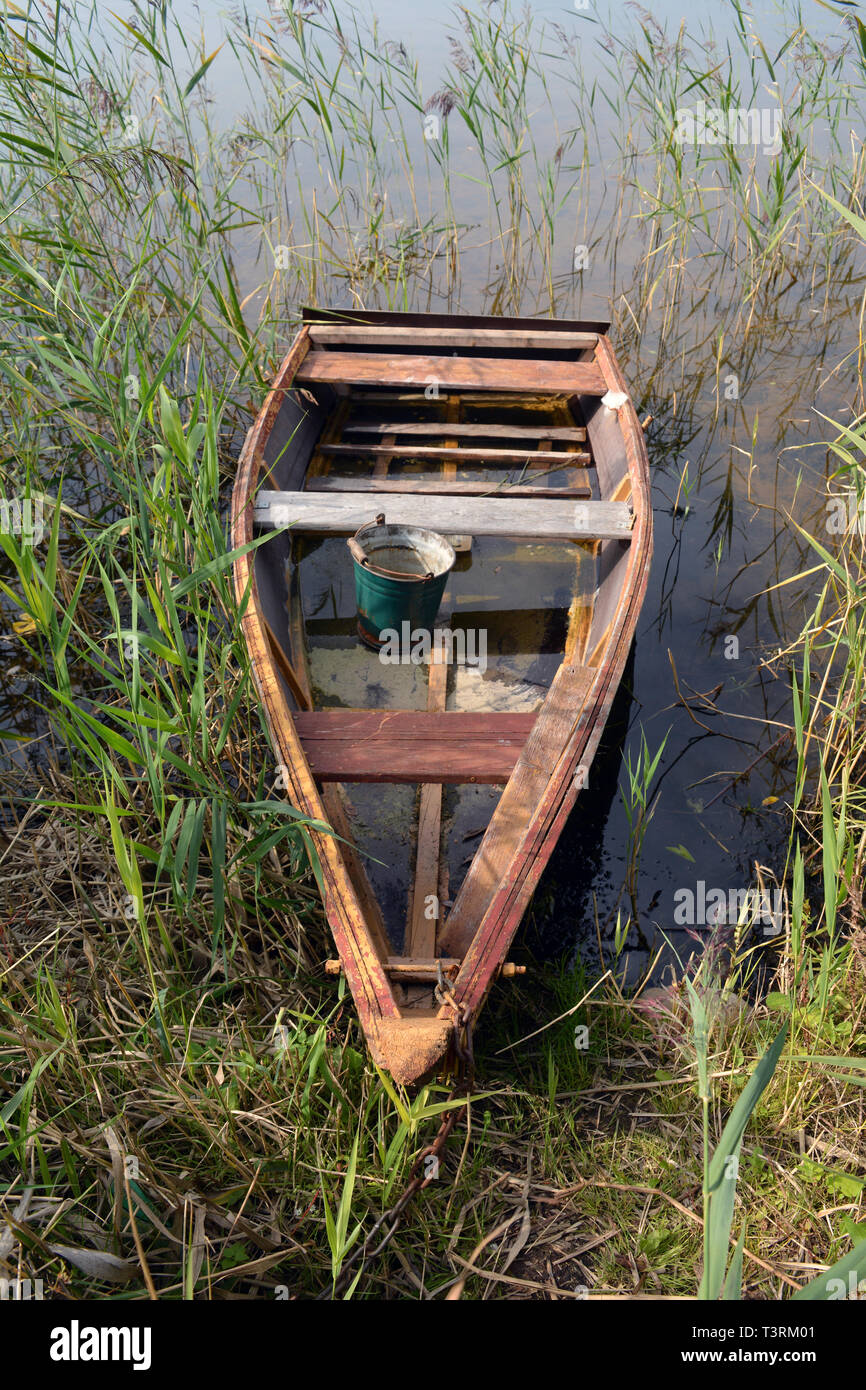 Wooden old used fishing boat on the lake in autumn Stock Photo