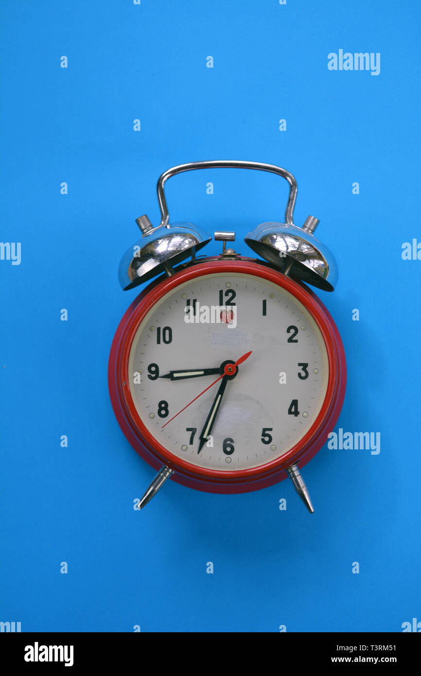 red old retro style used alarm clock on blue background Stock Photo