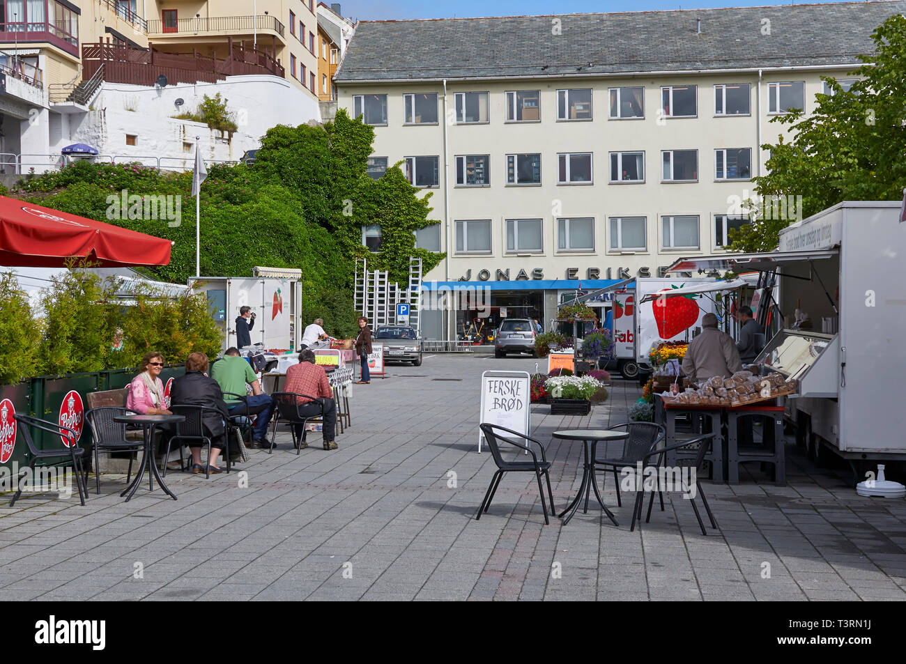 People buying and sitting down at Tables at a small Local Produce Market in a street in the Norwegian town of Kristiansund. July, Norway Stock Photo