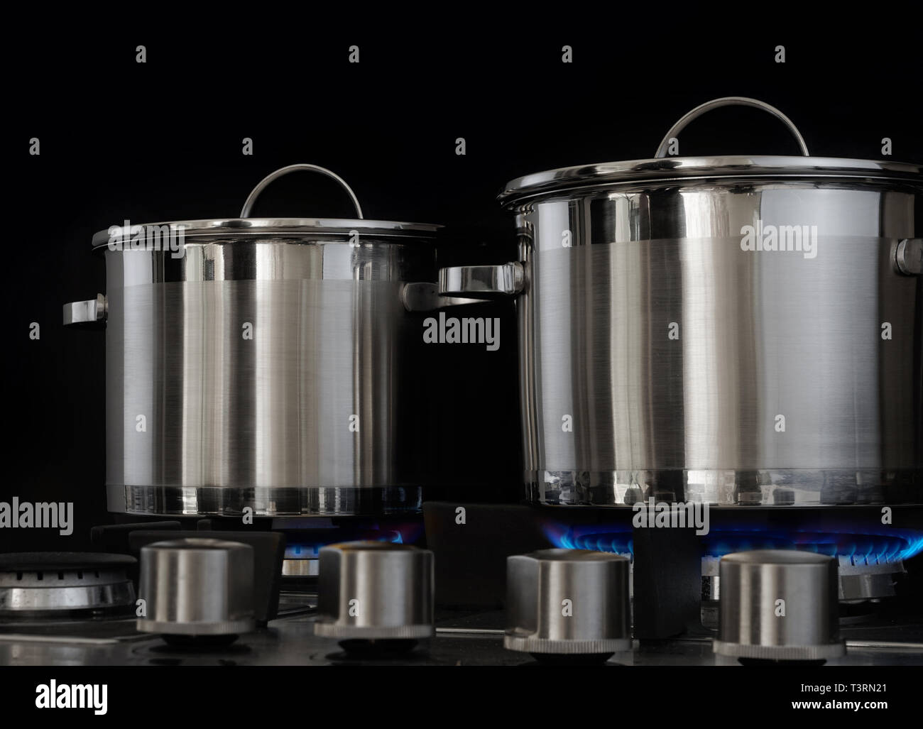 Metal pots in the kitchen, gas stove on, blue flame burning Stock Photo