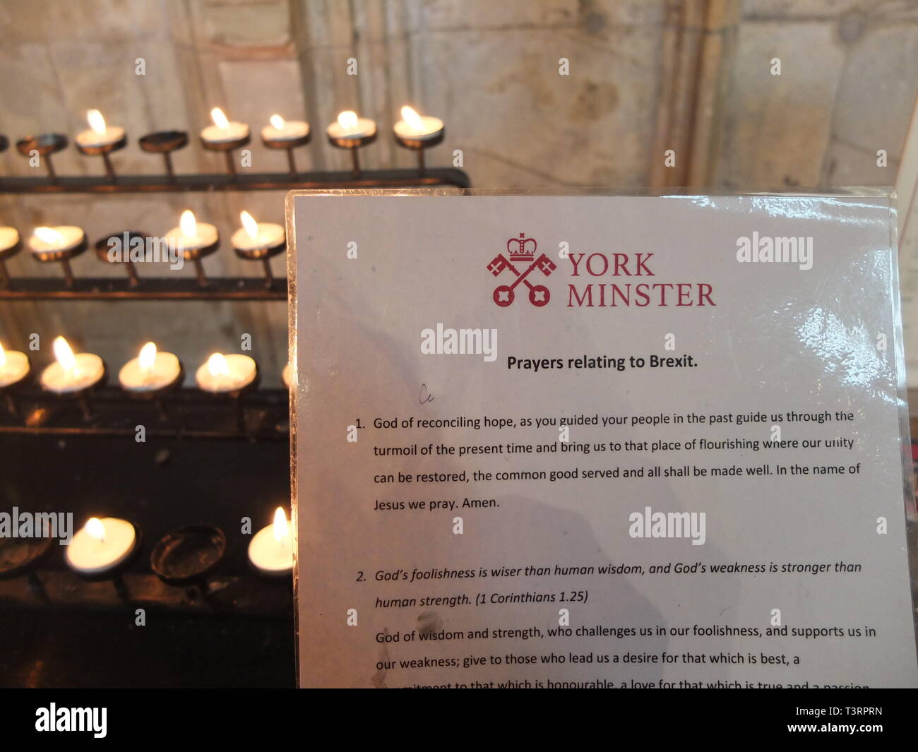 A selection of Prayers relating to Brexit on laminated card issued for visitors to York Minster UK. Backdrop of prayer candles. Brexit and religion. Stock Photo