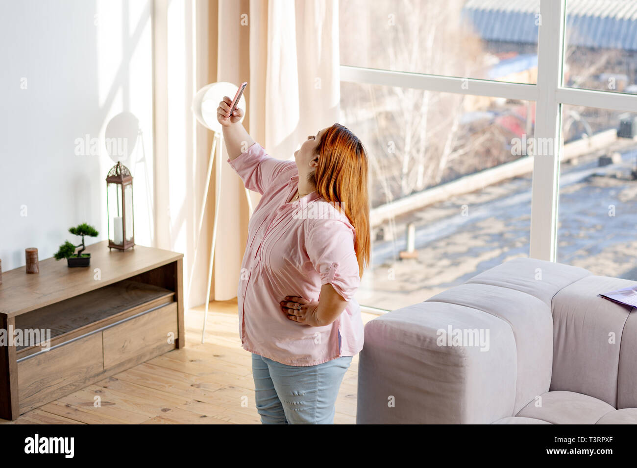 Joyful good looking woman looking into the smartphone camera Stock Photo