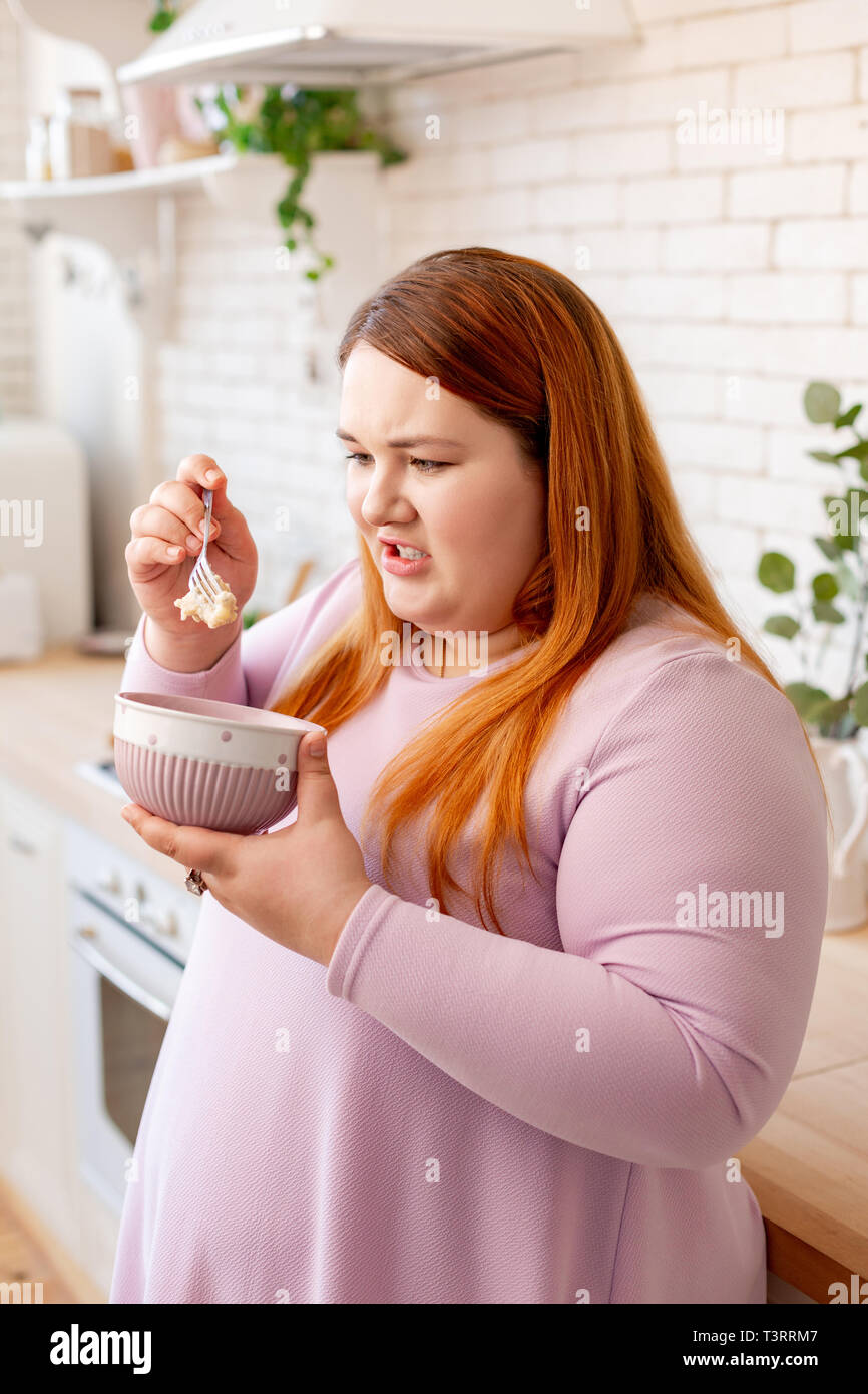 Unhappy plump woman looking at the oatmeal Stock Photo