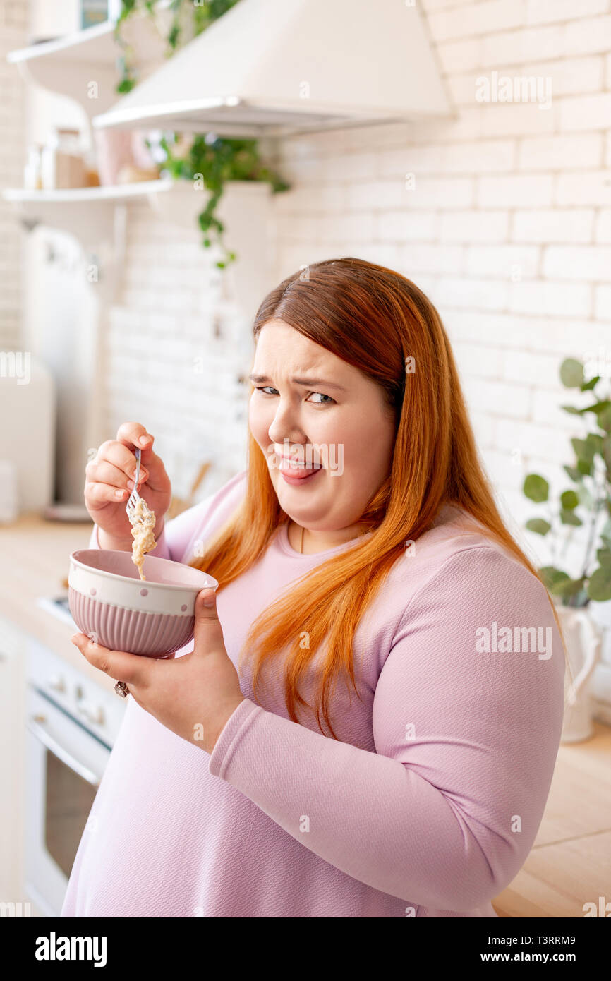 Cheerless gloomy plump woman hating her oatmeal Stock Photo
