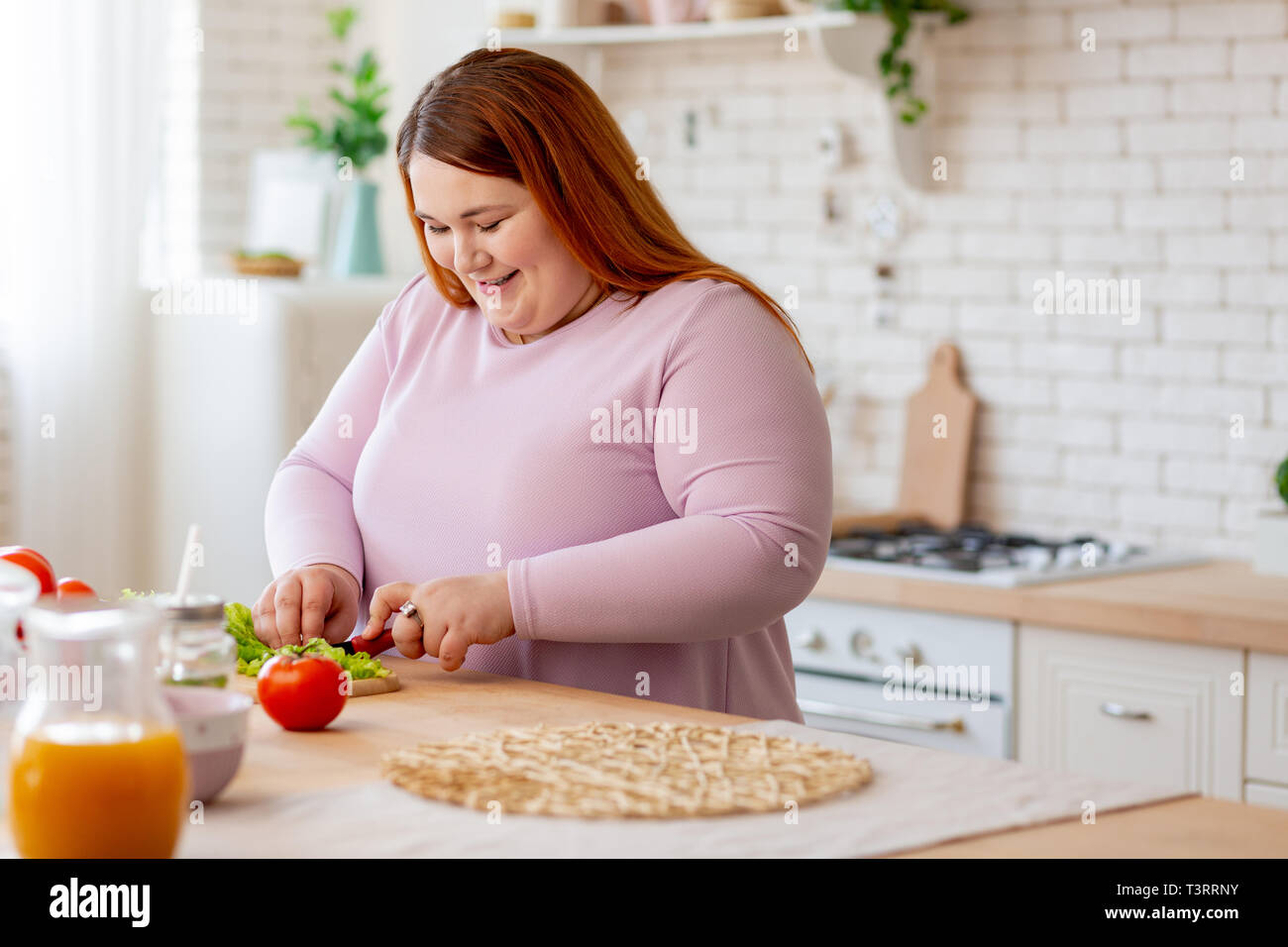 Positive delighted woman cutting lettuce for salad Stock Photo Alamy