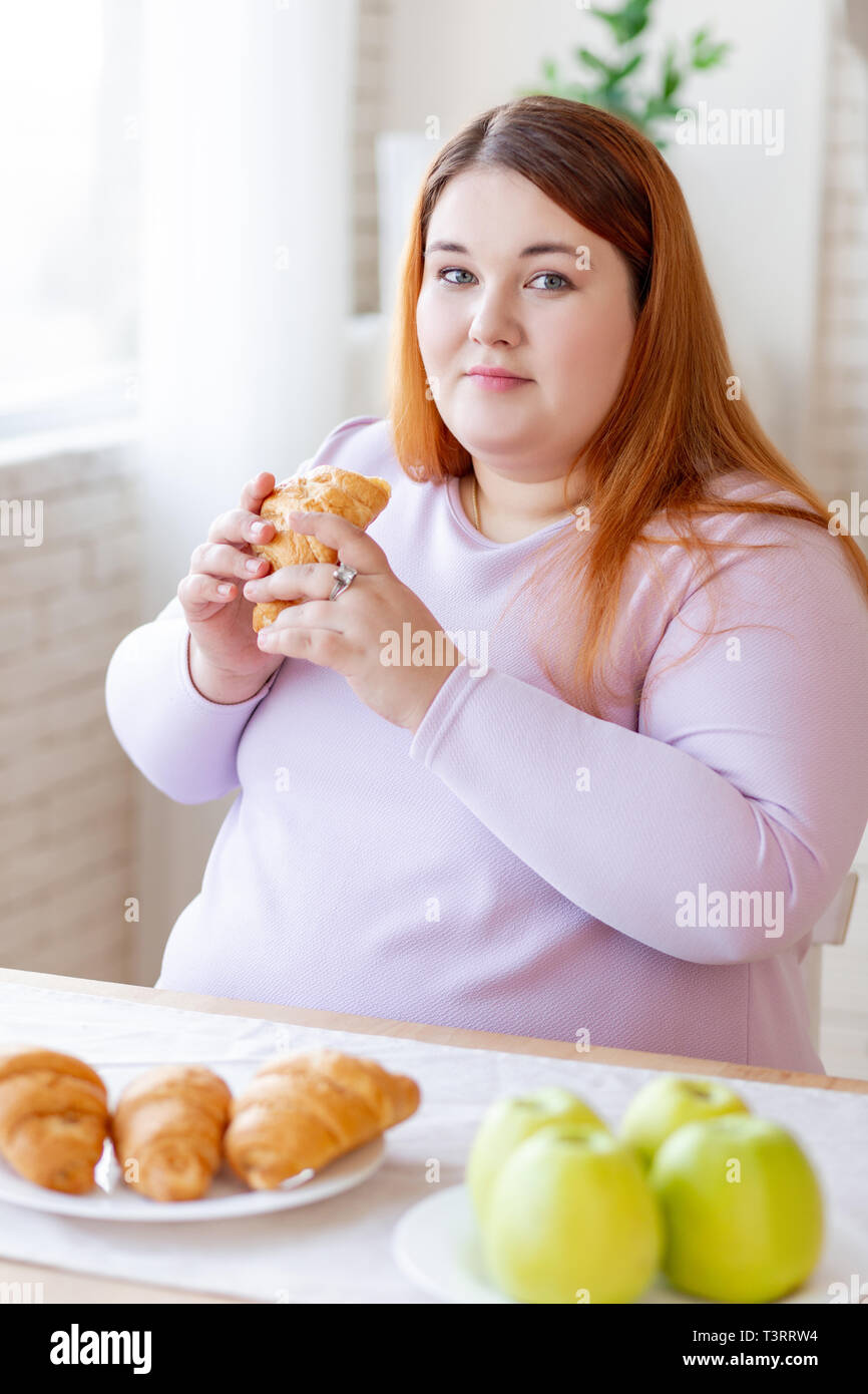 Nice plump woman holding a tasty croissant Stock Photo