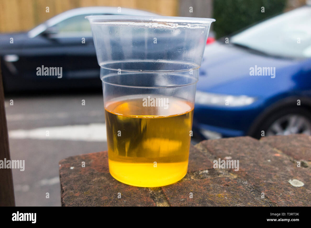 Moving car driving past a half empty plastic beaker of lager to illustrate the theme of drunk / drink driver, & driving while under the influence of alcohol. England UK (108) Stock Photo