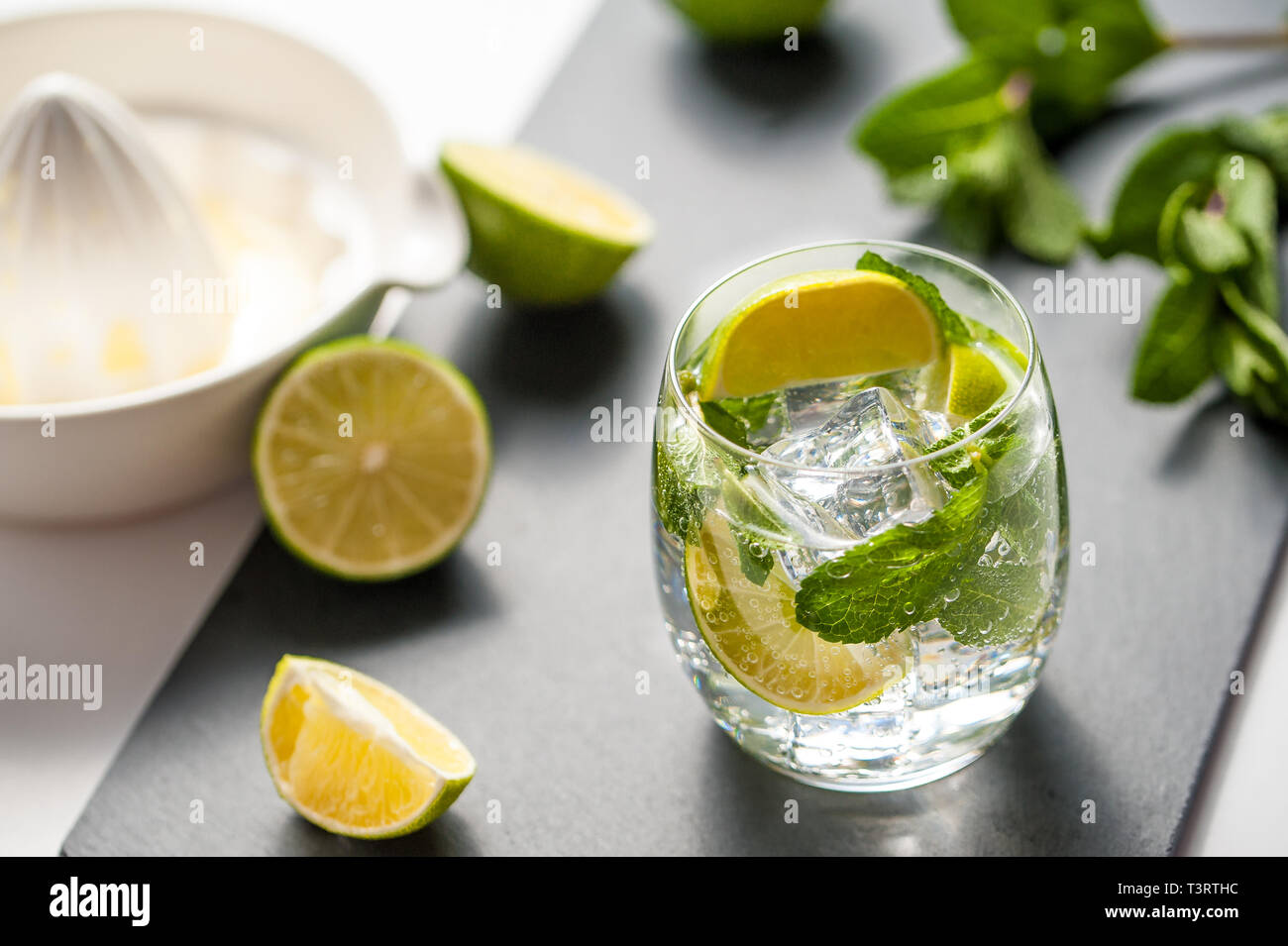 Summer cocktail concept: fresh mojito on chopping board with green limes Stock Photo