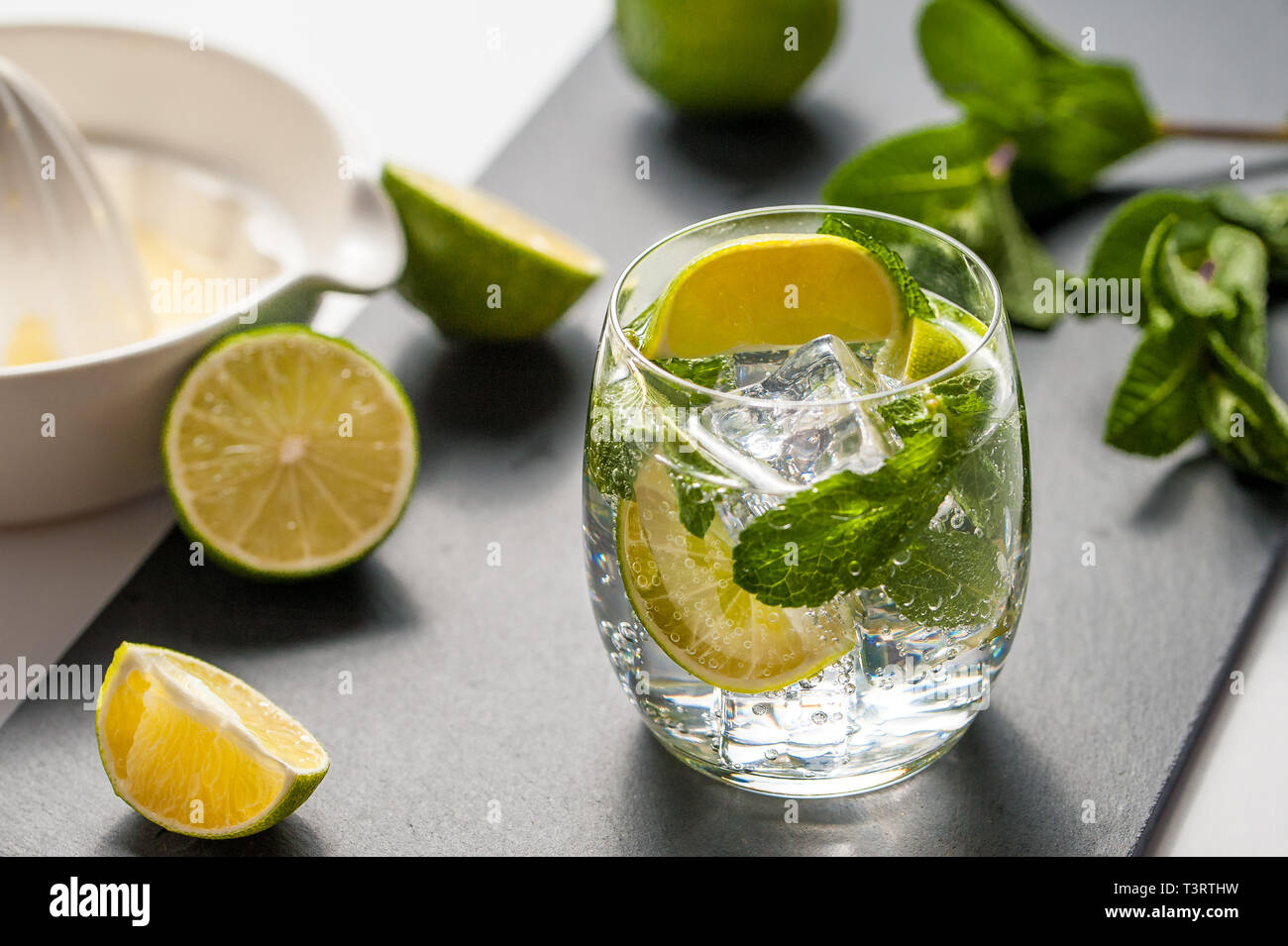Mojito cocktail on a stone board with fresh lime fruits and peppermint