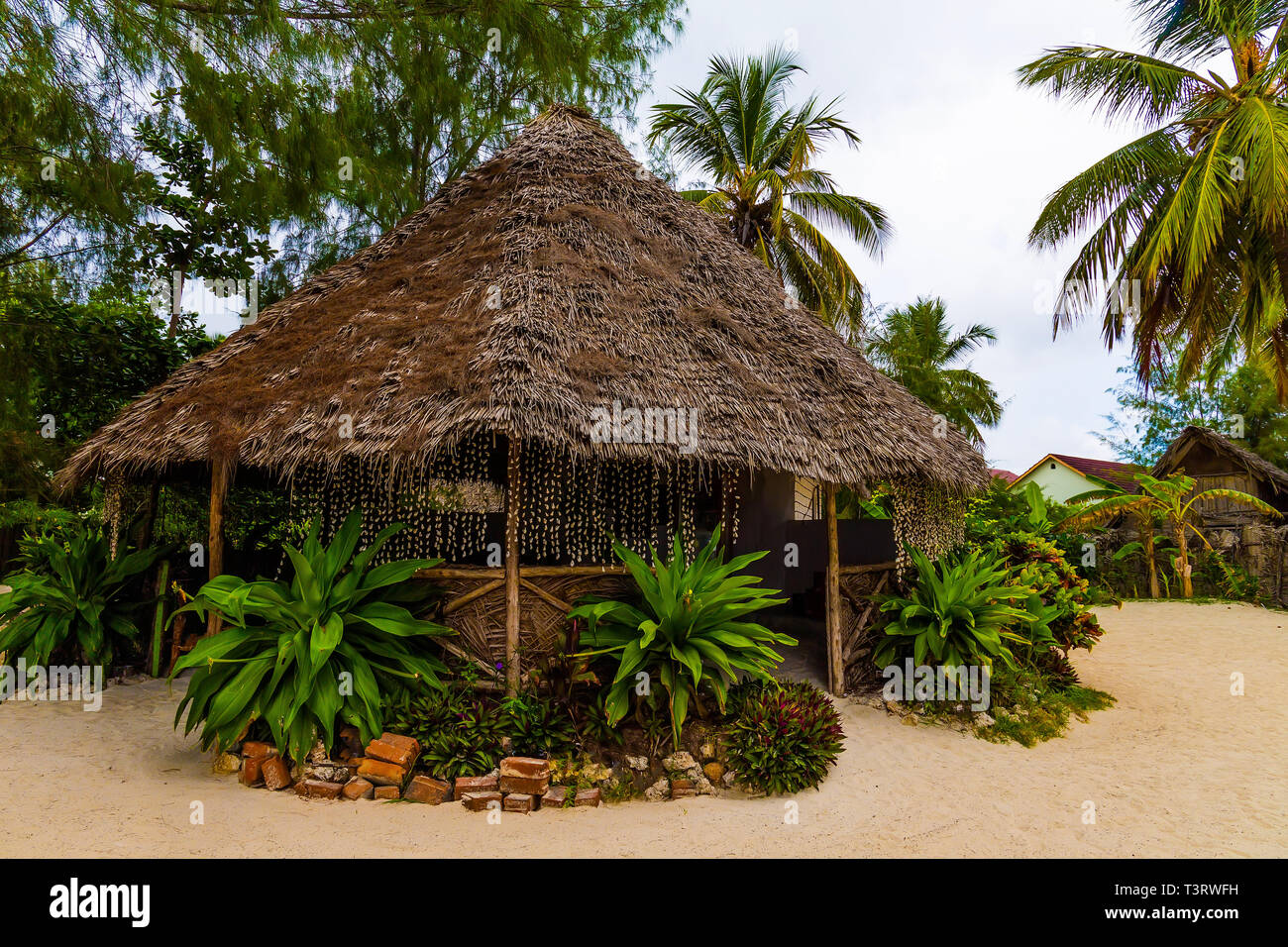 Thatched arbor on the beach on the white sand and green palm trees around. Stock Photo