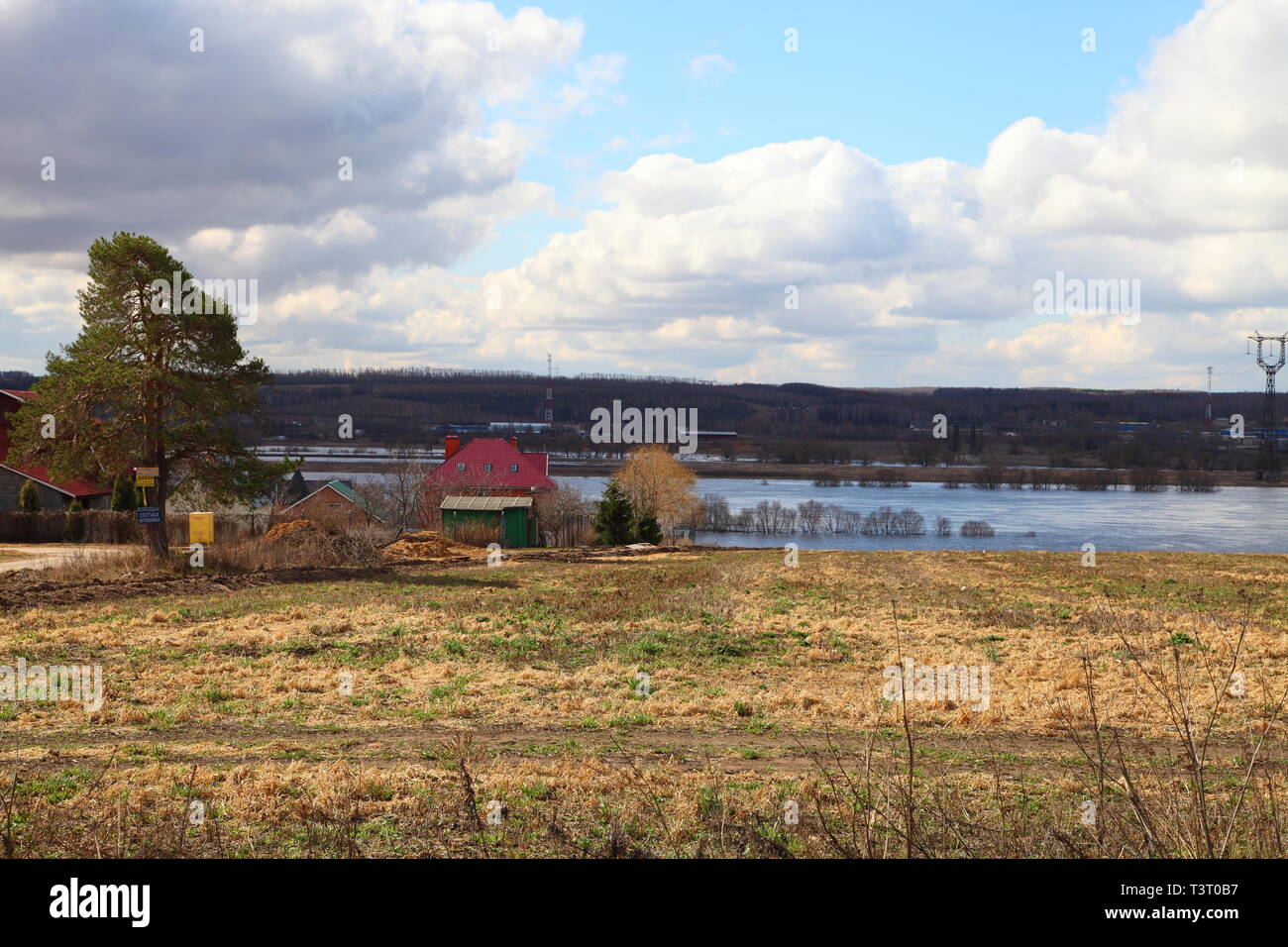 House with a red roof on the river bank. Spring flood of the river. Stock Photo