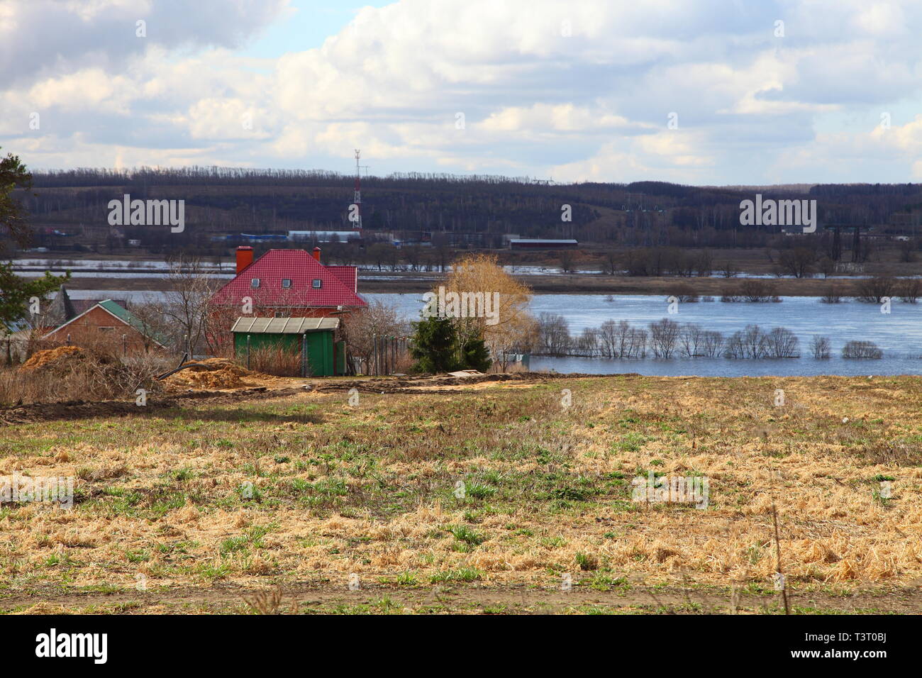 House with a red roof on the river bank. Spring flood of the river. Stock Photo