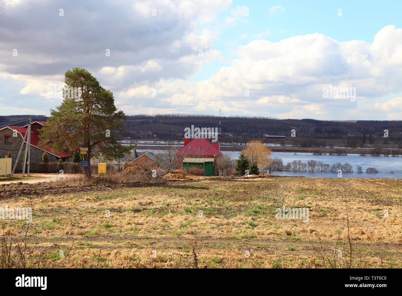 House with a red roof on the river bank. Spring flood of the river. Stock Photo