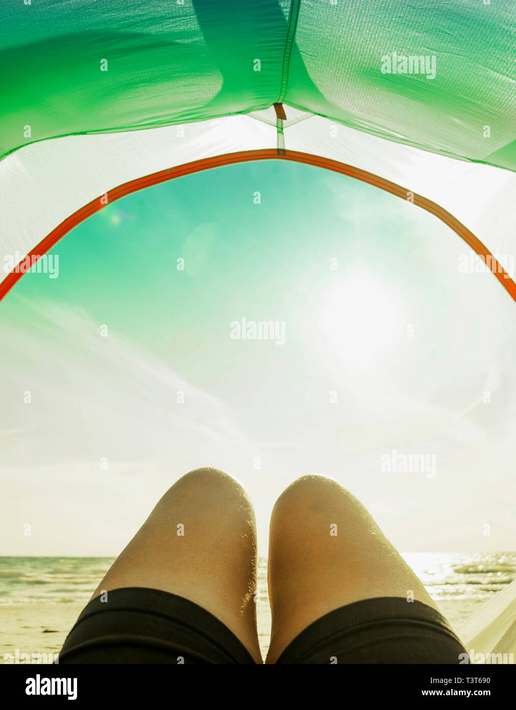 Legs in camping tent door on beach Stock Photo