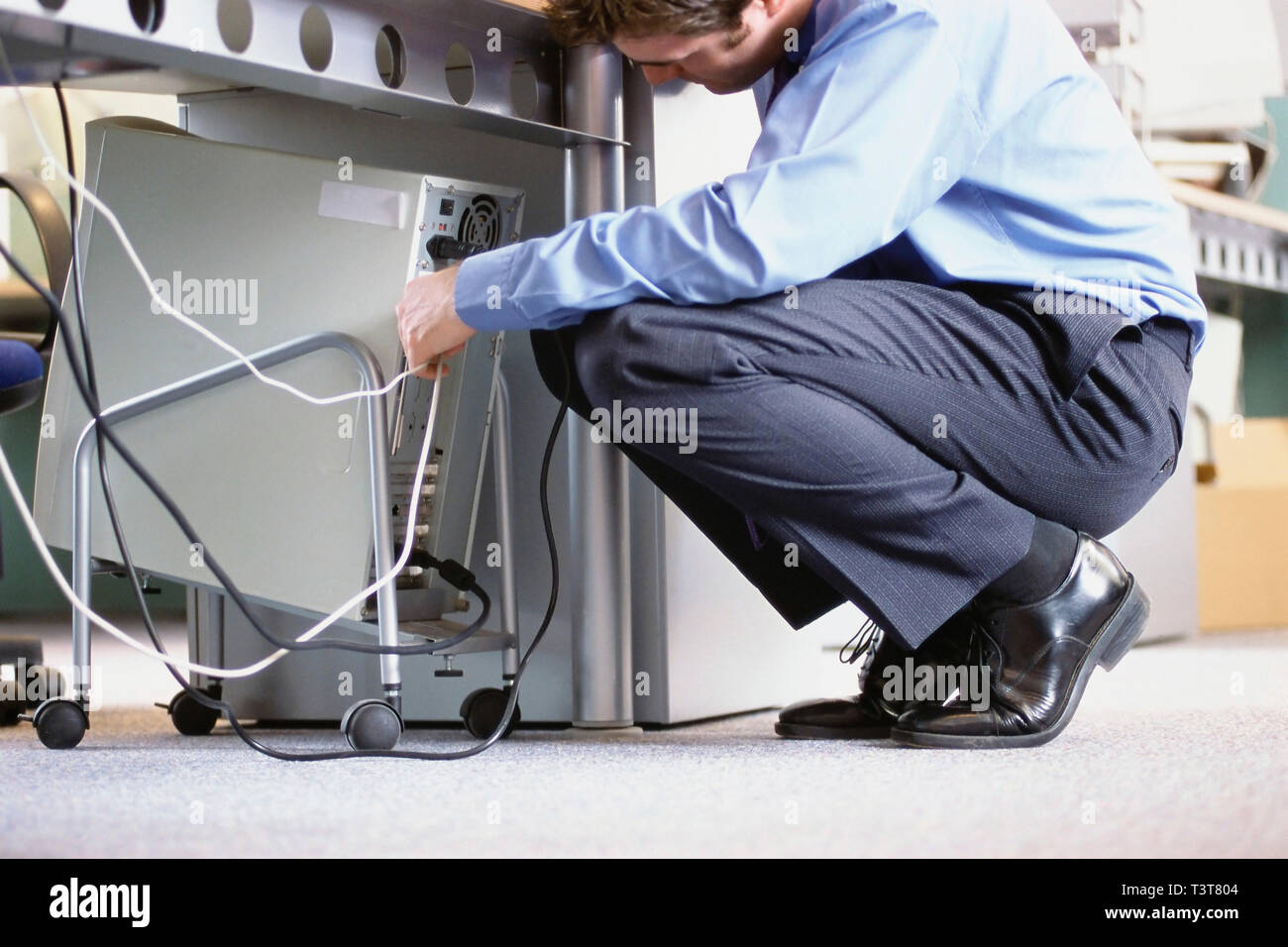 Caucasian businessman connecting cables to computer in office Stock Photo