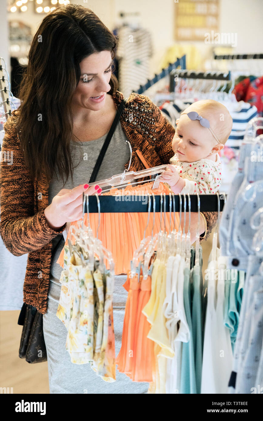 Caucasian mother and baby daughter shopping in clothing store Stock ...